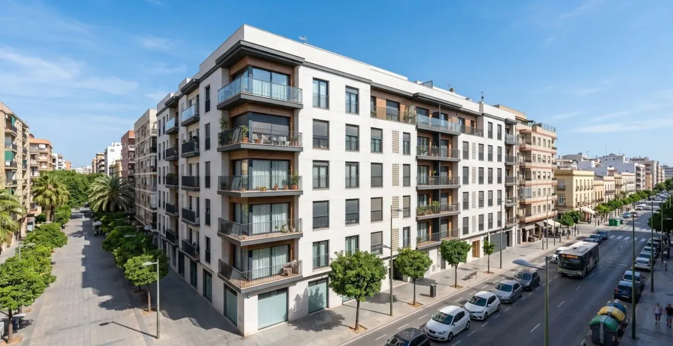 Fachada de un edificio residencial moderno español en entorno urbano bajo un cielo despejado y luminoso